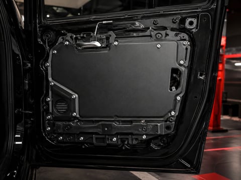 Open car door showing interior panel with mechanical components and fasteners exposed